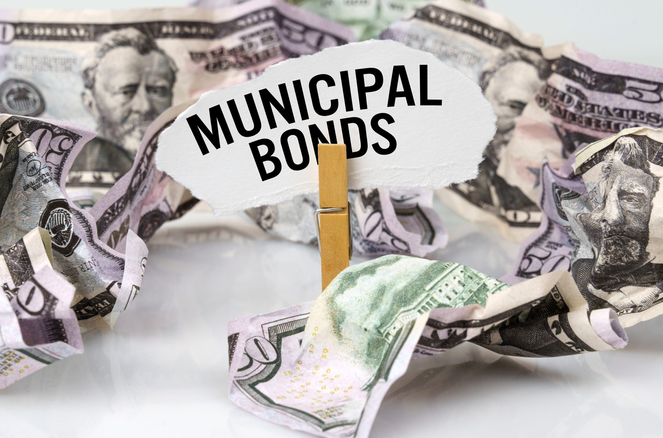 Business and finance concept. There are dollars on the table and there is a clothespin with paper on which it is written - MUNICIPAL BONDS